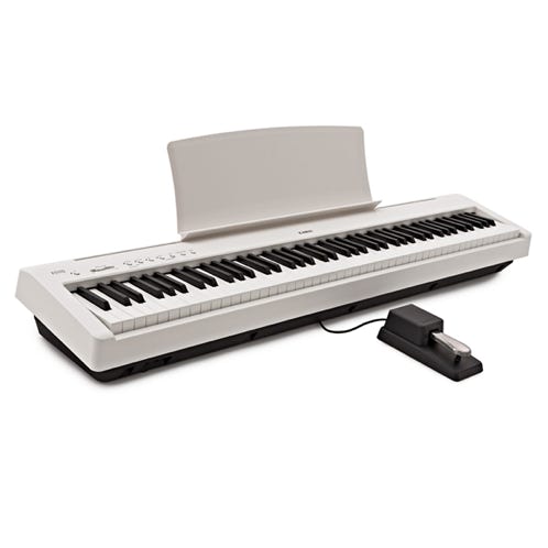 A child kneels at a bench playing an electronic keyboard indoors.